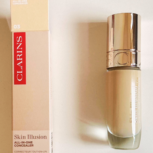 Photo of Clarins Skin Illusion All-in-One concealer in a sleek cylindrical glass bottle, highlighting sustainable cosmetic packaging.