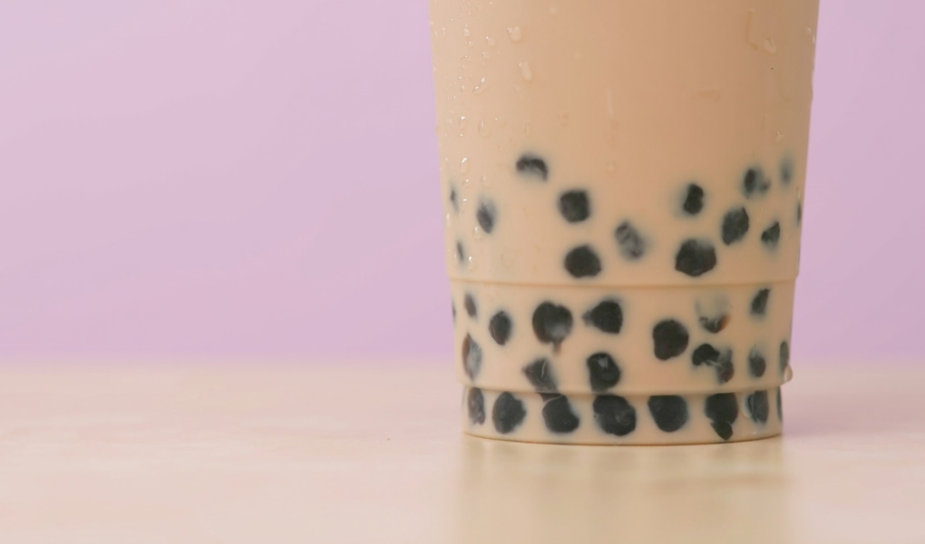Up close image of bubble iced tea with pink background.