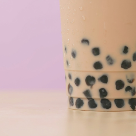 Up close image of bubble iced tea with pink background.