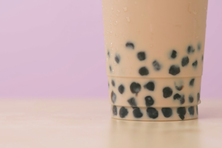 Up close image of bubble iced tea with pink background.