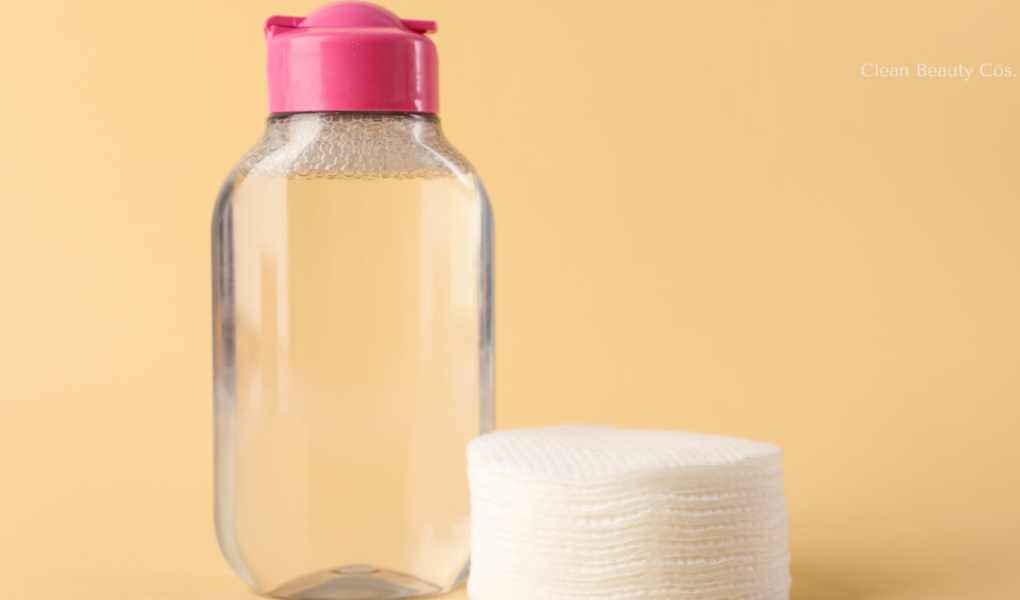 A minimalist bottle of micellar water placed next to a stack of clean cotton pads