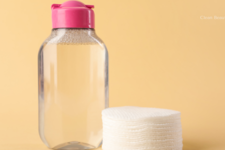 A minimalist bottle of micellar water placed next to a stack of clean cotton pads
