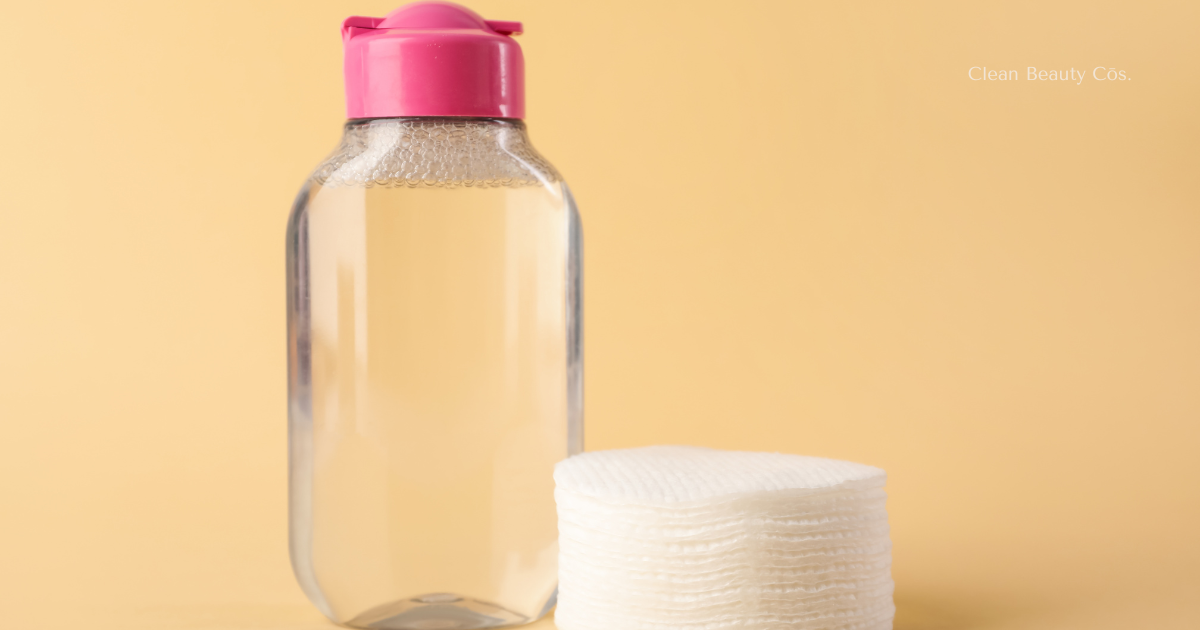 A minimalist bottle of micellar water placed next to a stack of clean cotton pads